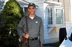 ai_heating_summertuneup_om Service tech standing in front of house