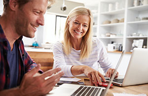 Couple smiling while looking at laptop