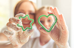 Woman and child holding up cookie cutters