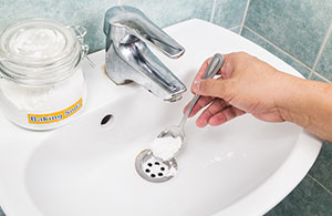 Person pouring baking soda down drain